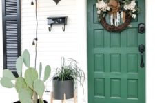 23 a planter with a cactus and a planter with greenery on a stand match the green door and a wreath adds charm