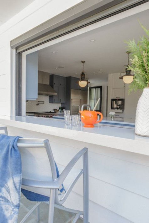 a roll up window with a white countertop and comfy chairs is ideal to have an outdoor meal