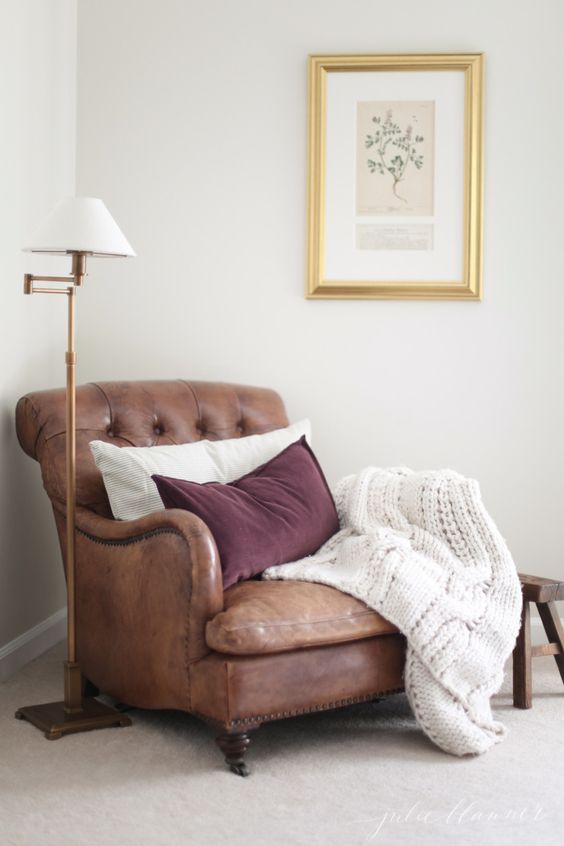 a vintage-inspired leather chair in brown with pillows and a knit blanket is always a good diea to try