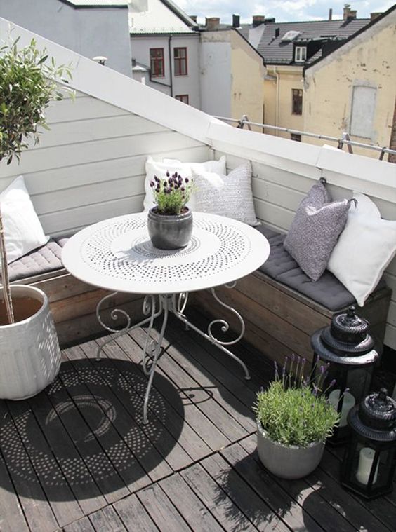 pillows, candle lanterns, potted greenery and blooms make the balcony more inviting and welcoming
