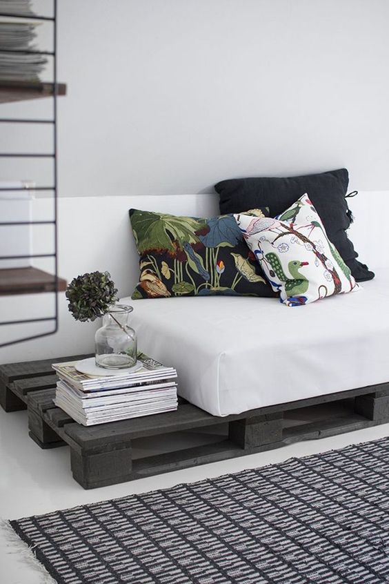 a dark stained pallet daybed with a comfy mattress and printed pillows is a cool idea for a living room