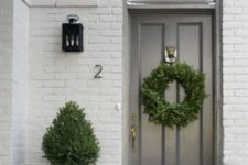 24 a single black planter with a tree and a matching wreath on the door make up a catchy and welcoming porch