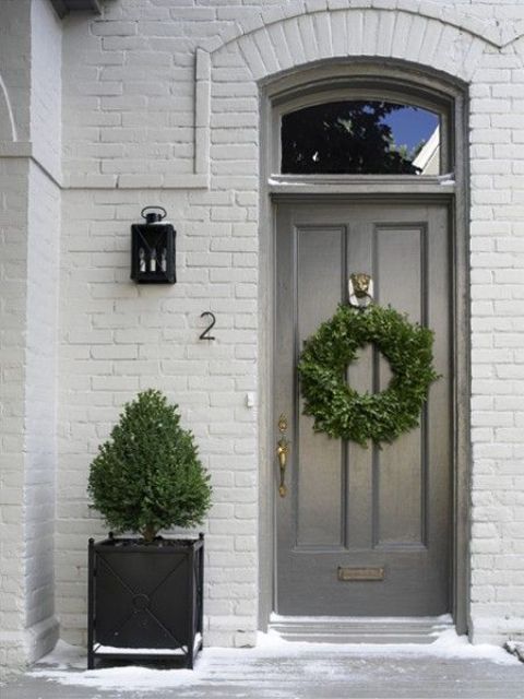 a single black planter with a tree and a matching wreath on the door make up a catchy and welcoming porch