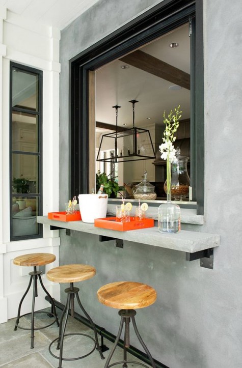 an oversized roll up window and a small concrete tabletop and metal and wood stools for an industrial feel