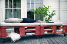 25 a bright red pallet daybed with cutout storage spaces, casters and comfy cushions