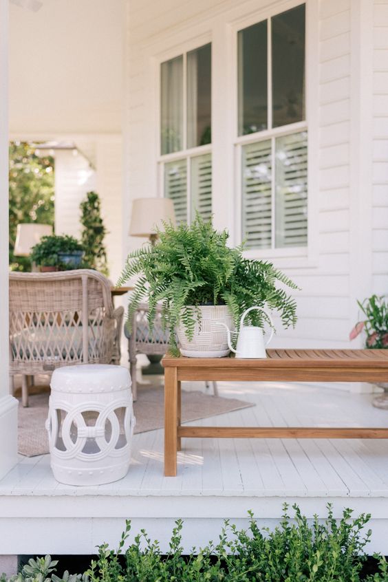 potted greenery, a small coffee table and a watering can for decorating a front porch