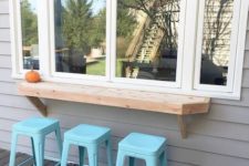 26 a simple window, a thick wooden tabletop and bright blue stools for a simple rustic space