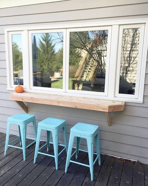 a simple window, a thick wooden tabletop and bright blue stools for a simple rustic space