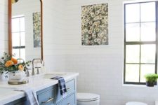 a colorful eclectic bathroom with a blue vanity, a colorful rug and a floral artwork