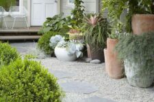 a modern front yard with gravel and rock paths, greenery and succulents, greenery and succulents in oversized plants is a stylish space