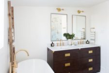 an art deco meets boho eclectic bathroom with lots of brass, boho rugs and a dark stained vanities