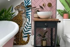 an attic bathroom with white walls and hex tiles, bold walll mural, a pink bathtub, a black vanity with a bowl sink