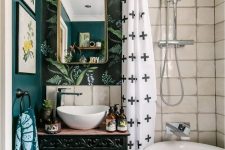 an eclectic bathroom with a dark green, botanical wallpaper and white tile wall, a vanity with books, bold textiles and a tub