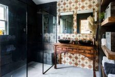 an eclectic bathroom with dark walls in the shower and star printed ones, a vintage vanity with two sinks and greenery