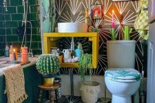 an eclectic bathroom with green and geometric tile, a yellow vanity with a sink, a bold rug, some artwork, potted plants and a round mirror