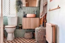 an eclectic bathroom with green and rust and white tile, white appliances, a stained vanity, a mirror, a woven pendant lamp and a gallery wall
