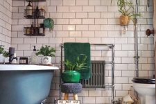 an eclectic bathroom with white and star printed tiles, a blue clawfoot tub, white appliances, potted greenery and green towels