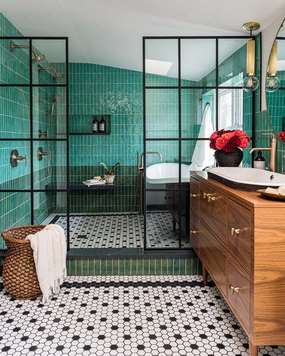An eye catchy bathroom with green skinny tiles, black and white hex ones, a stained vanity, a sink and a bathtub is amazing
