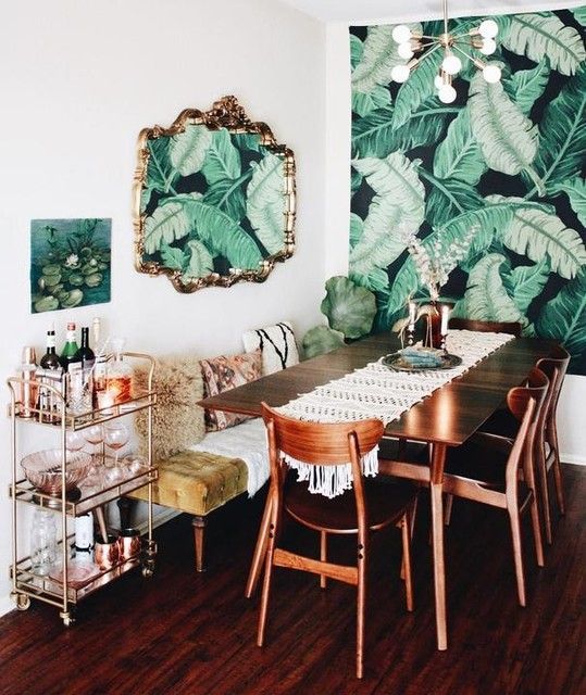a dining room with a tropical leaf print wallpaper wall and a matching artwork on the next wall for an accent