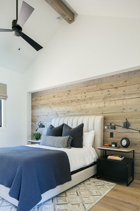 A modern farmhouse bedroom with a statement neutral colored shiplap wall that adds coziness and helps to pull off the style