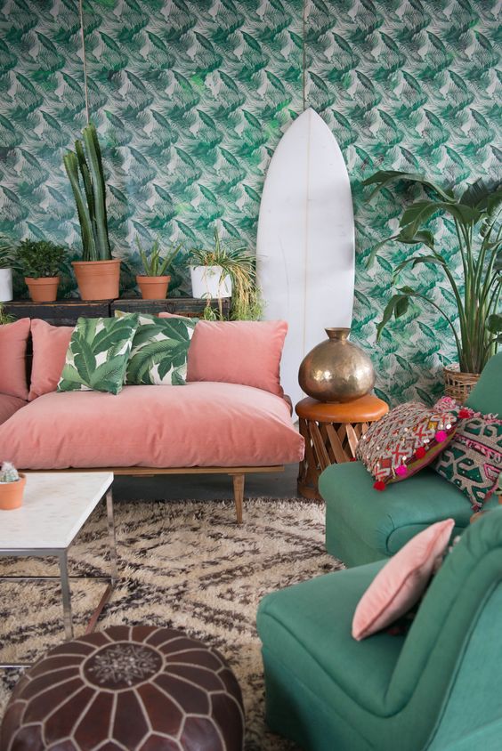 a bright living room with tropical leaf print wallpaper and matching pillows plus colorful furniture