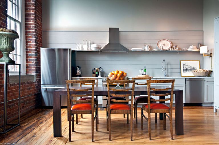 a chic kitchen done with grey shiplap that features a statement wall and a backsplash and orange chairs for a touch of color