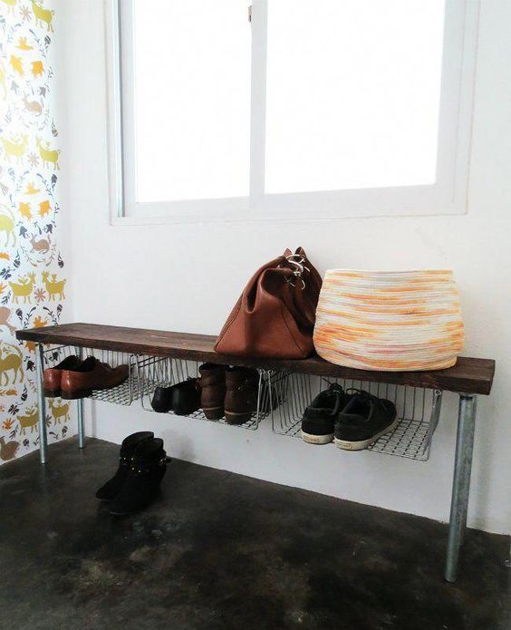 an industrial bench with metal legs, a wooden seat and wide shelves for storing shoes is a genius idea