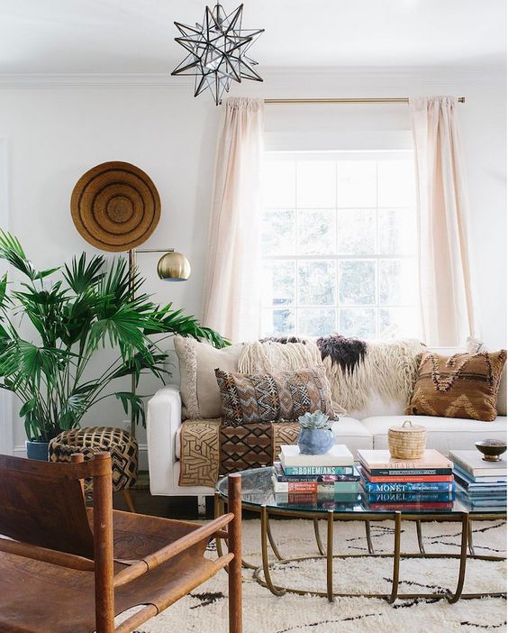 various printed and fringed pillows, a rug and a pritned upholstered ottoman for a boho living room