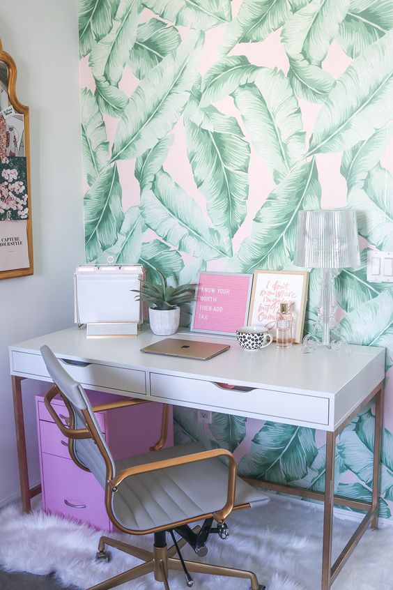 a girlish home office with banana leaf print wallpaper, touches of pink and brass