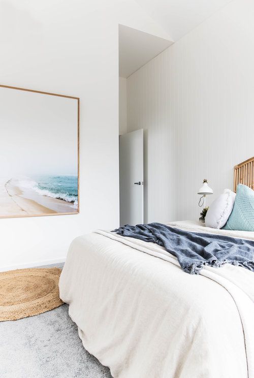 a neutral coastal bedroom done in white, off-white and light grey plus touches of aqua