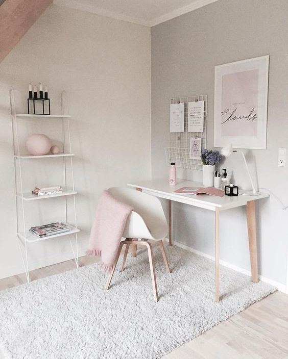 A feminine home office with touches of blush and wall mounted shelving unit that is delicate and airy