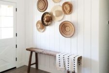 06 a simple entryway with a rough wooden bench and a white shiplap wall highlighted with decorative baskets and hats