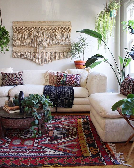 colorful printed pillows, a printed rug and a large macrame hanging make the space boho-like