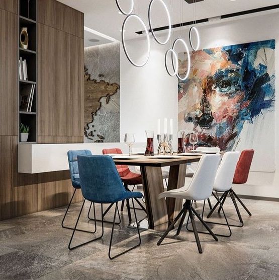 a contemporary dining room with white, red and blue mismatching chairs and a wooden table