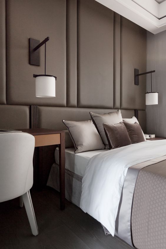 a taupe wall with upholstered panels over the bed substitutes the headboard and makes the space cozier