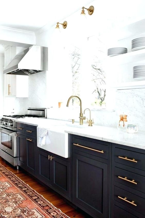 a chic black and white kitchen with gold hardware and matching lamps over the basin