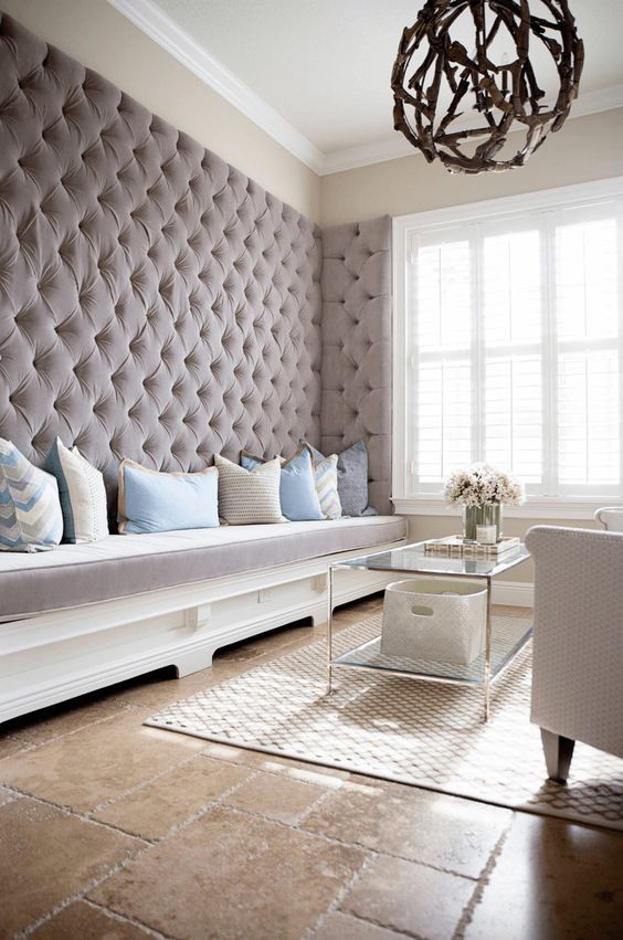A refined living room with an upholstered taupe wall with a built in bench brings luxury and coziness