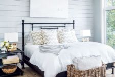 08 a welcoming farmhouse bedroom with light blue shiplap, a metal bed and a basket for storage