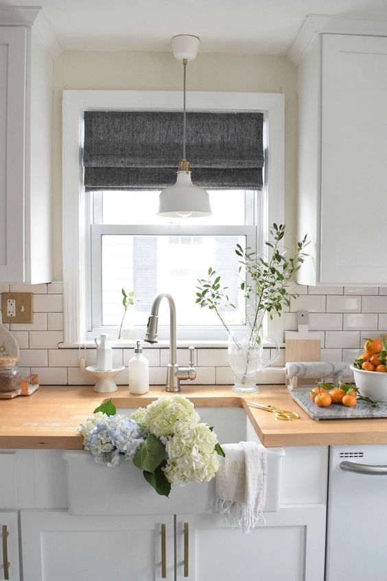 Grey Roman shades add a touch of color to the all white kitchen and keep it private when needed