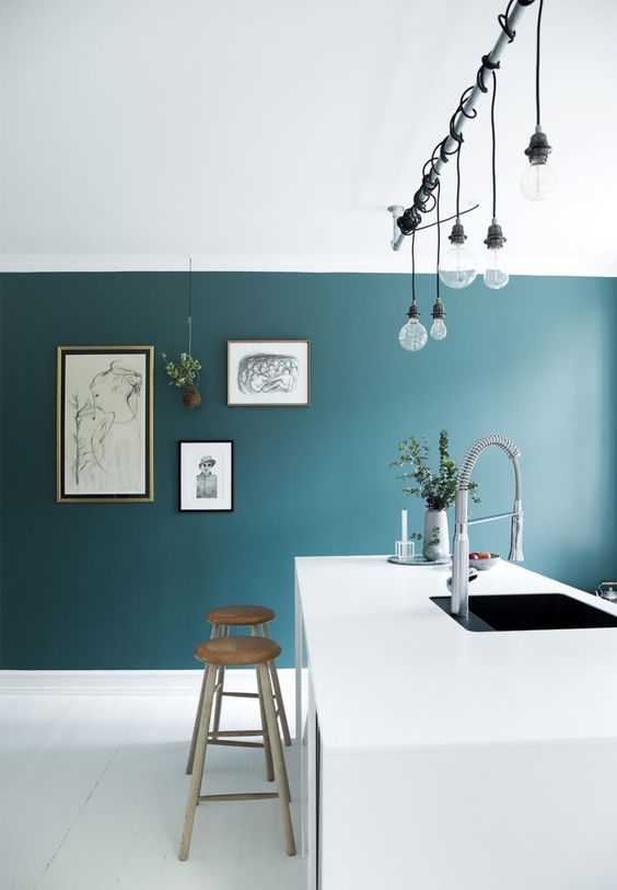 highlight a white ultra-minimalist kitchen with a teal accent wall plus a gallery wall on it