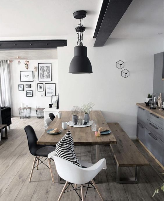 a contemporary dining space with a wooden table and bench plus black and white chairs for a fresh feel