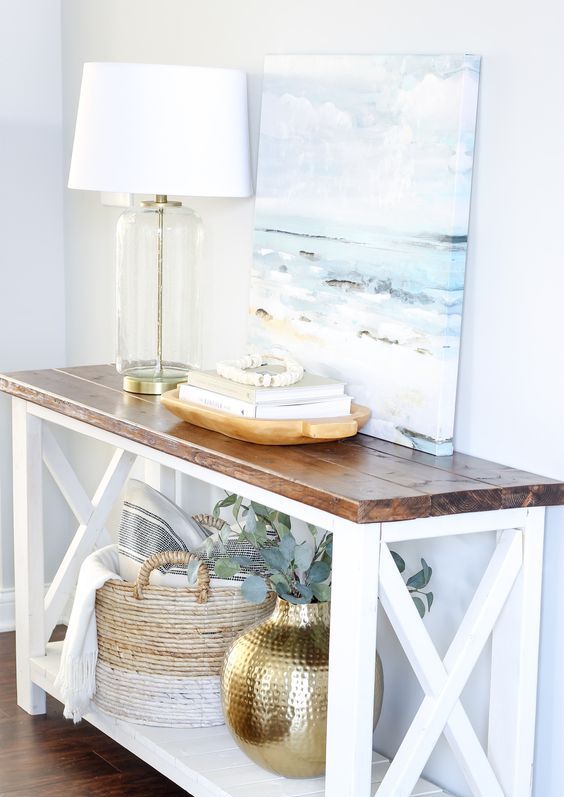 a rustic meets modern console table in white and with a rich stained tabletop for a coastal entryway
