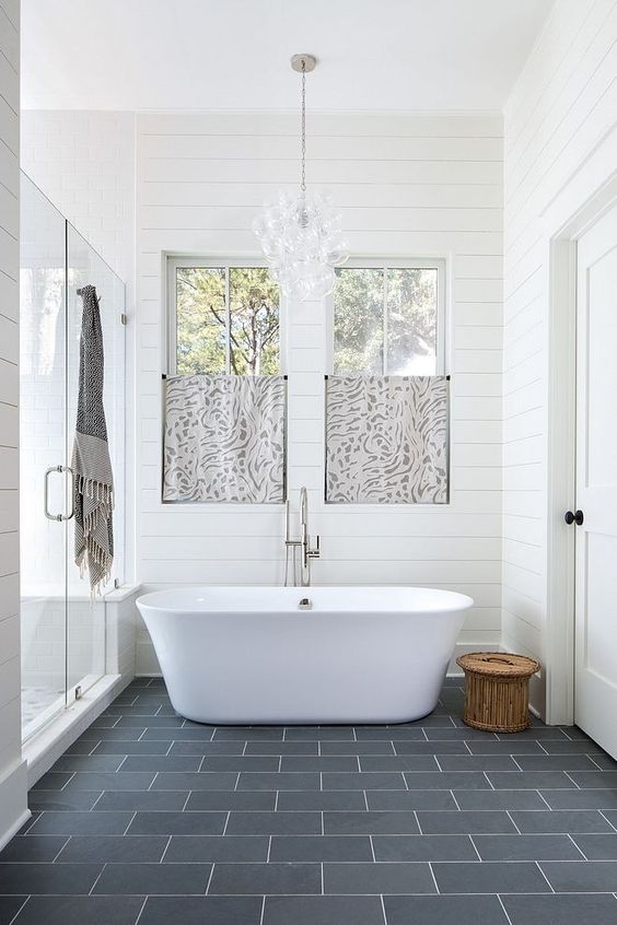 a beautiful master bathroom with shiplap walls, ample natural light, and freestanding soaking tub