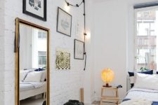 11 a dreamy Scandinavian bedroom with white brick walls, a whitewashed floor shows off black framed art and dark bedding