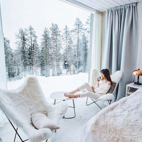 a couple of fur covered chairs, a side table by the glazed wall create a chic space to enjoy the views and breathe in that frosty air