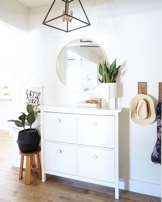 a geometric framed chandelier with brass touches adds chic to the entryway lighting it up