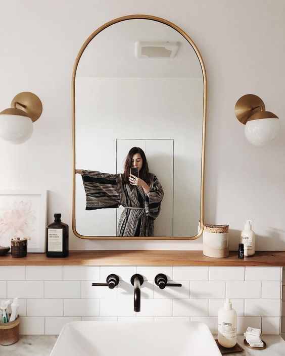 an elegant arched gold frame mirror and matching wall lamps to add chic to your bathroom