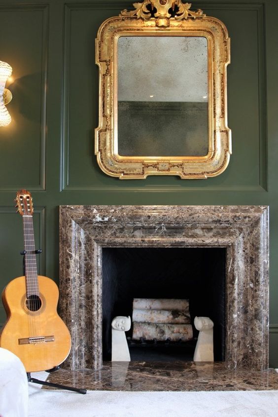 a huge antique gold framed mirror makes a refined statement in this room and looks beautiful on a green wall