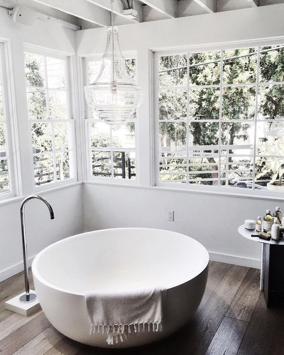 A bowl shaped bathtub placed by the windows to fill this space with light and enjoy the views