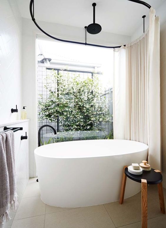 a contemporary bathroom with an oval tub and a view to the inner courtyard with much greenery
